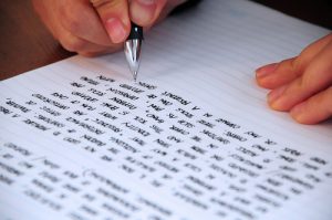 Image of a person writing on a lined piece of paper.